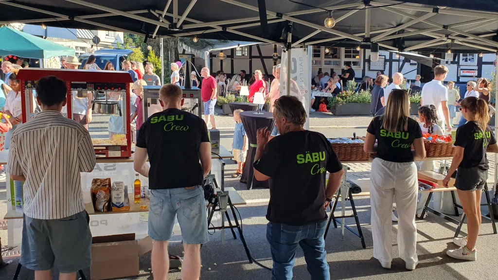 Rückenansicht des SÄBU-Teams in schwarzen Crew-Shirts am Messestand auf der Langen Nacht in Morsbach.